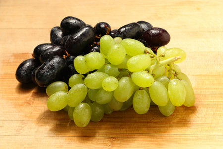 Fresh green grapes and black grapes fruits . Isolated on wooden background