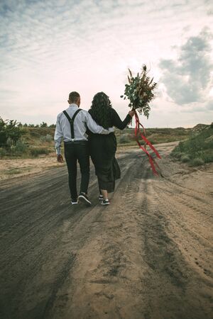 A man and a woman are walking along the road with a bouquet of flowersの写真素材