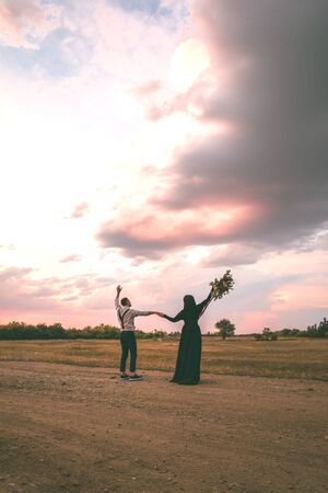 A man and a woman in nature look at the sunset skyの写真素材