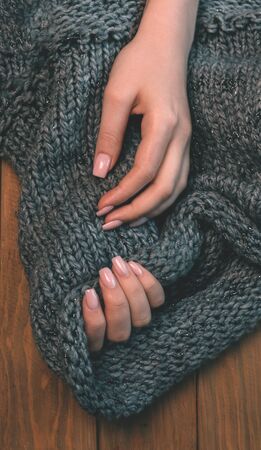 Womens hands on a knitted fabric on a wooden backgroundの写真素材