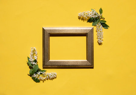 Golden frame of white flowers and leaves on a yellow background