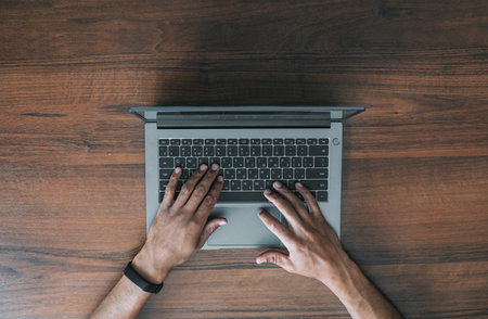 Mens hands in black electronic watches on the keyboard of a laptop against the background of a...