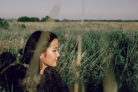A girl is sitting in a field on the grass in natureの写真素材