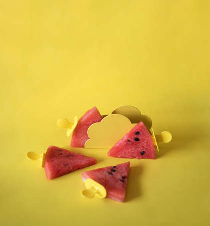 Watermelon slices on an ice cream stick on a yelloow background. Creative idea top viewの写真素材