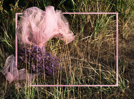 Grass field with scarf and bouquet of wild flowers background with pink border. The view from the top. Copy space for text.の写真素材
