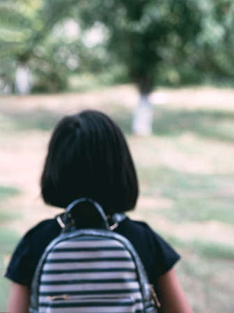 Blurred background with a picture of a girl. Back to school. Little girl with a backpack goes through the alley. Child from elementary school. Education.の写真素材