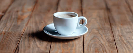 Cup of coffee on an old wooden table. White ceramic. Aromatic coffee with foamの写真素材