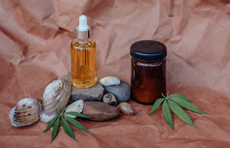 Glass bottle and dropper CBD OIL, THC tincture and cannabis leafs on pastel background. Laboratory Production of cosmetics with CBD oil. Top viewの写真素材