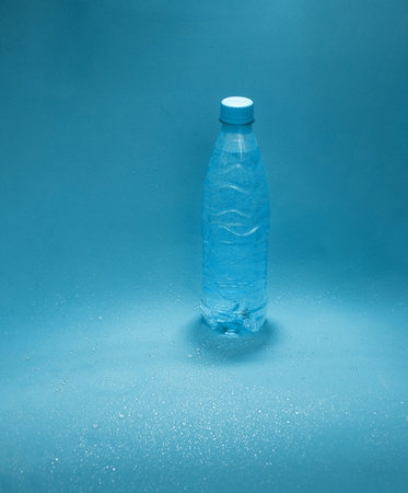 Blue plastic water bottle on  blue with water drops.の写真素材