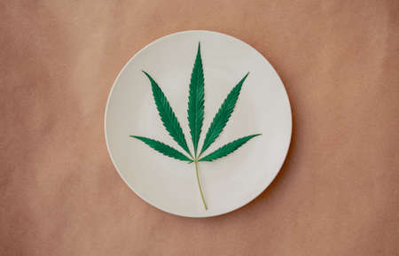 Cannabis leaf on a white plate. Floor tile background. cannabis live resin extraction on kraft background. Medical marijuana concept. Top viewの写真素材