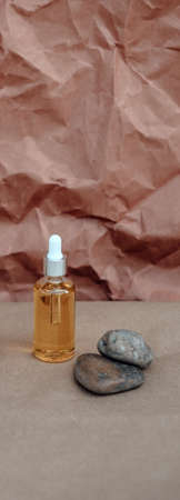 Organic Spa Cosmetic With Herbal Ingredients. Vegetable serum for skin. Serum with herbal extracts. Serum in a transparent glass bottle with a pipette on a kraft backgroundの写真素材