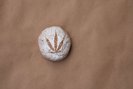 Pattern of cannabis leaf made with powdered sugar on the cookies on kraft background. Cannabis live...