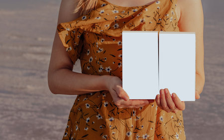 Girl in a yellow dress holds two isolated white boxes in her hands outdoors