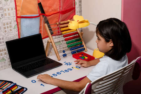 Asian schoolgirl studying homework math during her online lesson at home, video call zoom with laptop at home. New normal.Covid-19 coronavirus. Social distancing. Stay homeの写真素材