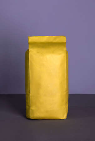 Small blank bulky yellow package with product on a purple-lilac background . Ready for shipping, delivery and sale. Small business artisan concept.の写真素材
