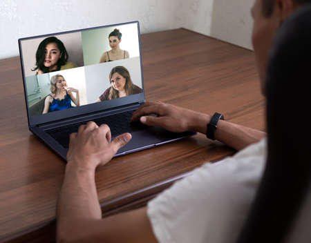 Back view of businessman talking to his colleagues about plan in video conference. Multiethnic business team using laptop. Group of people smart working from home. Dating siteの写真素材