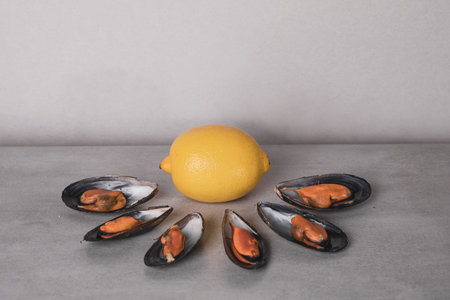 Seafood with lemon. The delicious, cooked mussels on a grey stone background. Minimalism in food...