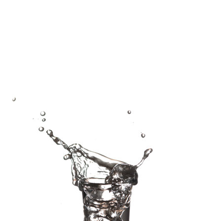 Splash in a glass on white isolated background Vodka on an old wooden table as detailed close-up shot. Transparent glass with liquid. Hand over glassの写真素材