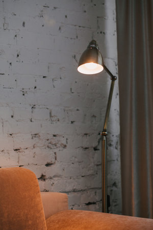 Golden floor lamp and orange comfortable sofa in an elegant living room interior with an old brick wallの写真素材