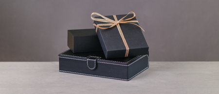 Back gift box. Golden ribbon on gift on a grey background. Copy space