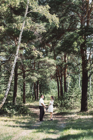 Stylish couple in the forest. A guy and a girl hug together under a large old tree on a background of a forestの写真素材