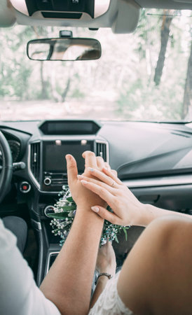 Picture of man and woman in a car. Married couple holding hands, ceremony wedding day. Newly wed couples hands with wedding rings.の写真素材