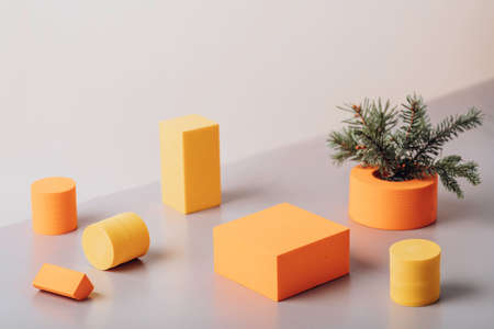 Orange and yellow podiums with a spruce branch on a beige background. New Years visualization. Festive background.の写真素材