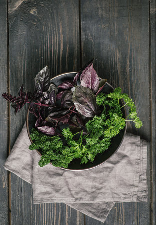 Fresh green vegan vitamin parsley, basil on rustic wooden background, napkin tablecloth, place for...