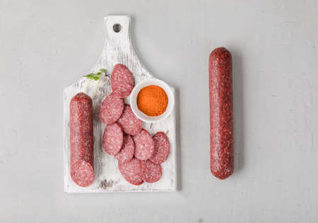 Classic salami on white chopping board with paprika on concrete background.の写真素材