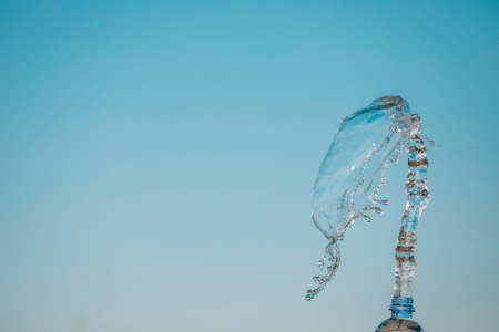 woman hand holding bottle of water on sky background. splashの写真素材