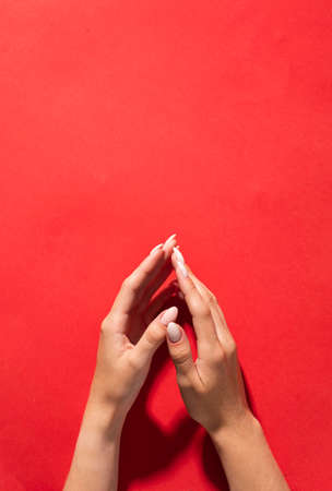 Stylish trendy female manicure. Beautiful womans hands on red background.の写真素材