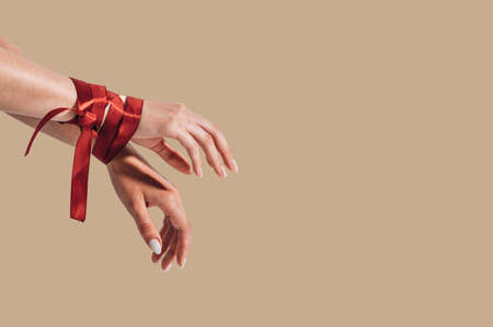 Female hands tied with a red satin ribbon. Human trafficking and abuse, International Human Rights day.の写真素材
