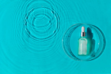 Cosmetic spa medical skincare, glass serum bottle with collagen on blue water background with waves....