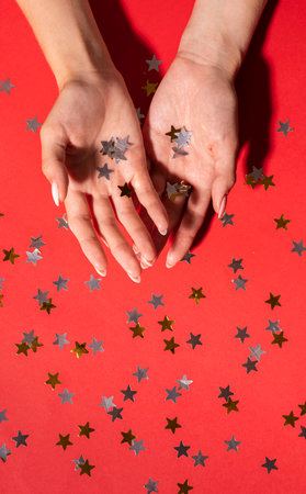 Stylish trendy female manicure. Beautiful womans hands on shine red backgroundの写真素材