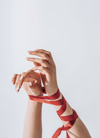 Female hands tied with a red satin ribbon. Human trafficking and abuse, International Human Rights day.の写真素材
