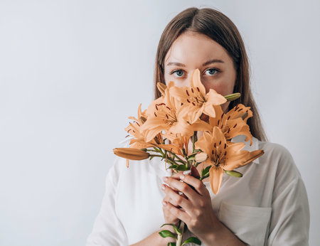 Beautiful young woman with fresh lilies on white background