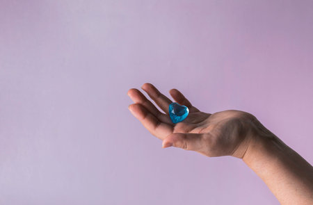 Blue glass heart in woman hand. Love concept on Valentine day.の写真素材