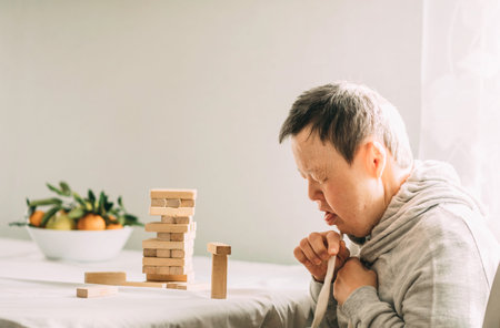 An elderly woman with down syndrome builds towers of wooden toy blocksの写真素材