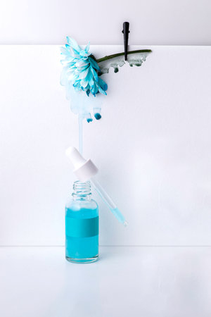 Serum or cream with floral extracts for skin care. Face and body care spa concept. Nature cosmetics in glass bottle with a pipette and with blue flower on white background.の写真素材