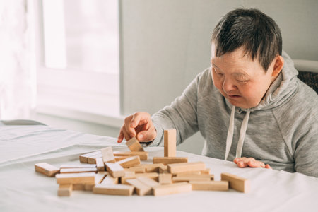 elderly woman with down syndrome and an Asian girl play in tower from wooden blocksの写真素材