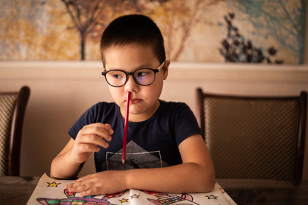 A bored little boy student inserted a pencil into his nose. The concept of ADHDの写真素材