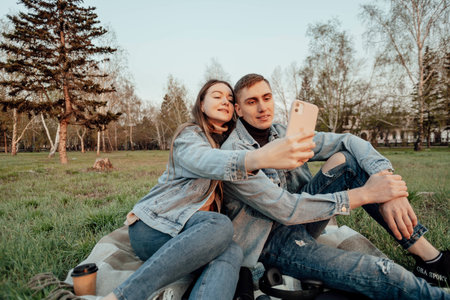 young fashionable couple smiles while looking at the phone in the park, selfieの写真素材