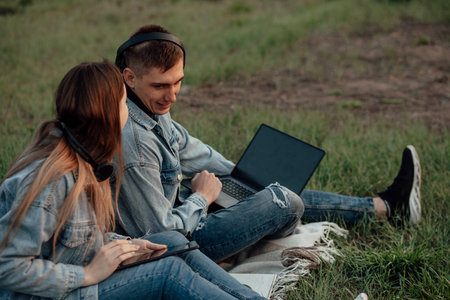 man and a woman with a laptop and tablet while working using laptop, sitting in parkの写真素材