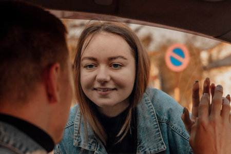 Happy couple or friends saying good bye through a car window before travelの写真素材