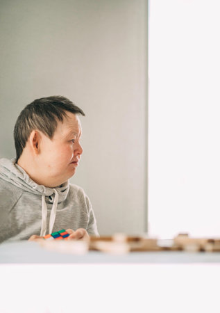 elderly Down syndrome woman at home play in tower from wooden blocks