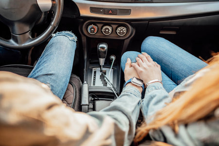 Close up cropped high angle shot of driver man, lady, holding each others arms, on their way to dreams and happiness, highway, feelings, friendship, destinationの写真素材