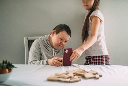 Young girls heartwarming assistance empowers elderly woman with Down syndrome to make phone callsの写真素材
