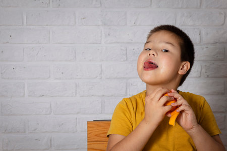Asian curious boy indulges in juicy orange, concept and benefits of vitamin C
