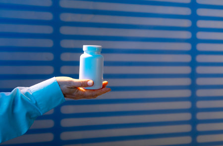 doctor holds sleeping pill to combat melatonin with insomnia against background of night ward with blindsの写真素材