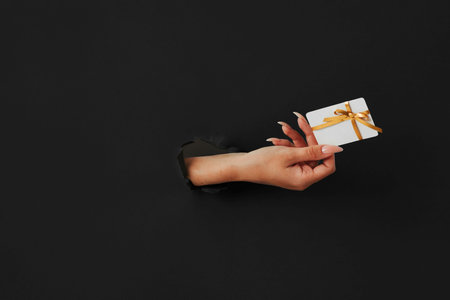 hand with credit card on a black paper background, the concept of black Fridayの写真素材